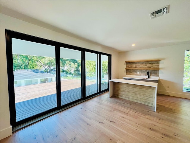 kitchen with tasteful backsplash, sink, and light hardwood / wood-style flooring