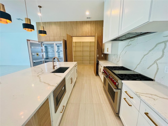 kitchen featuring sink, high end range, backsplash, decorative light fixtures, and white cabinets