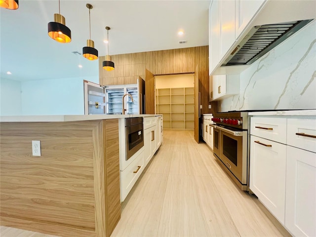 kitchen featuring white cabinetry, pendant lighting, extractor fan, and appliances with stainless steel finishes