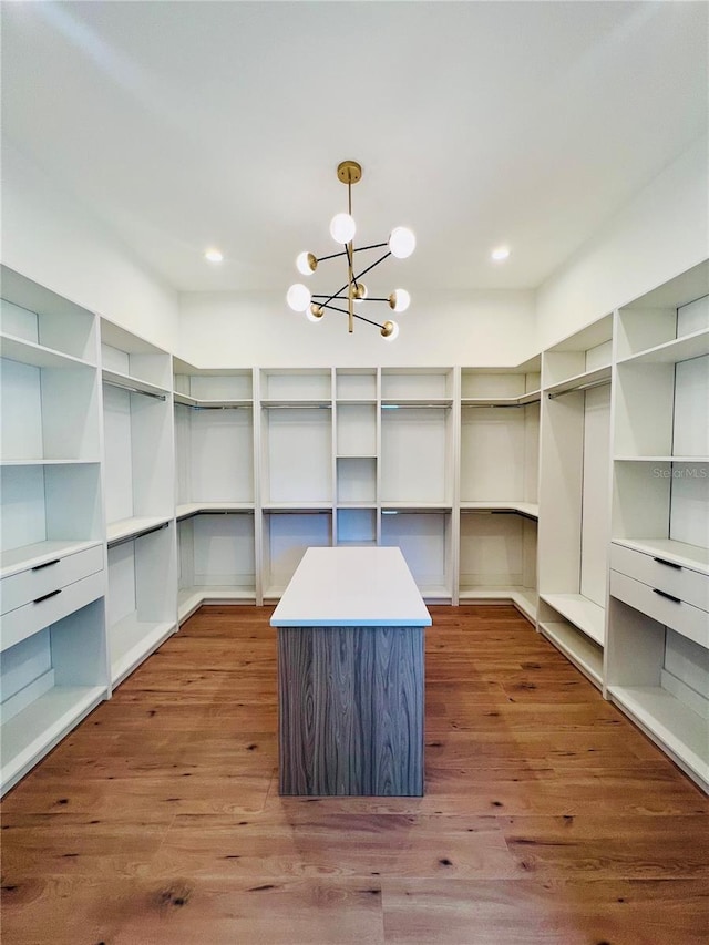 spacious closet with wood-type flooring and a notable chandelier