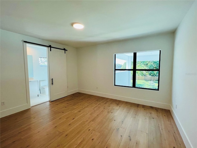 empty room featuring a barn door and light hardwood / wood-style flooring