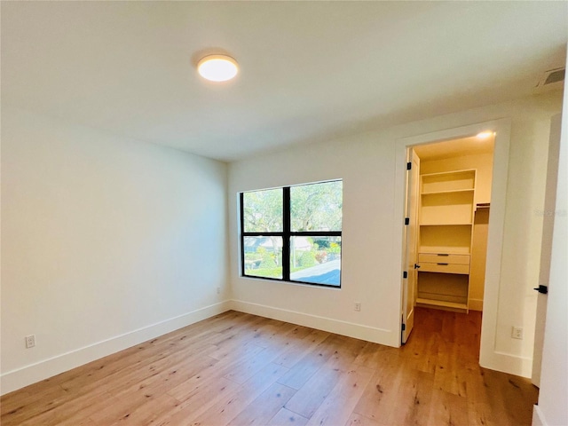 unfurnished bedroom with light hardwood / wood-style flooring, a spacious closet, and a closet