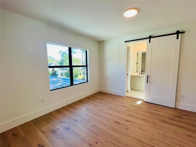 spare room with a barn door and light hardwood / wood-style flooring