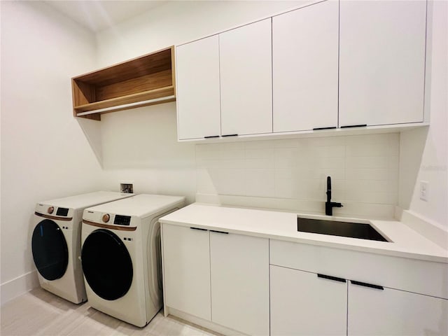 washroom with washer and clothes dryer, cabinets, and sink