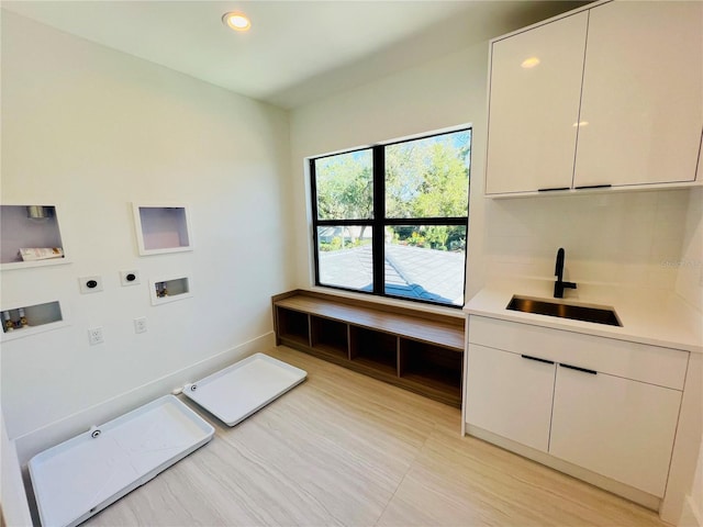 clothes washing area with electric dryer hookup, cabinets, sink, and hookup for a washing machine