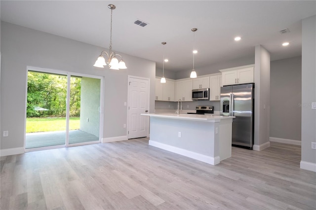 kitchen featuring light hardwood / wood-style flooring, white cabinets, hanging light fixtures, and appliances with stainless steel finishes