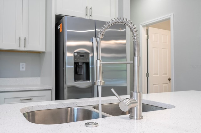 kitchen featuring white cabinets, light stone counters, and stainless steel refrigerator with ice dispenser