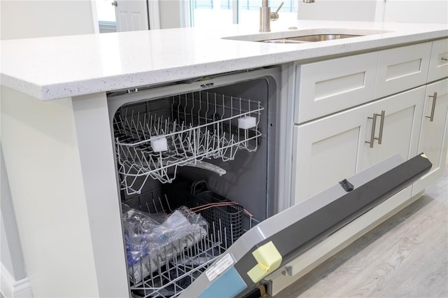 room details with white cabinets, dishwasher, sink, and light hardwood / wood-style flooring