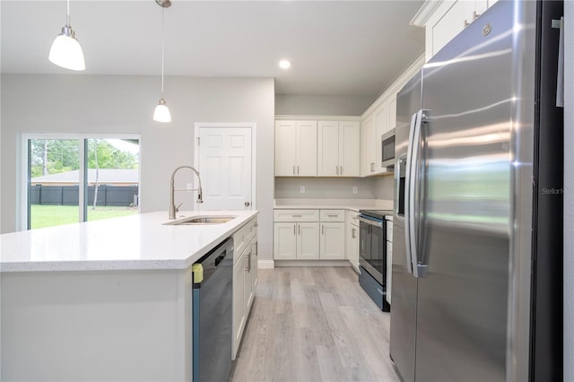 kitchen featuring pendant lighting, sink, light wood-type flooring, white cabinetry, and stainless steel appliances