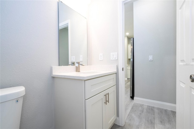 bathroom featuring hardwood / wood-style flooring, vanity, and toilet