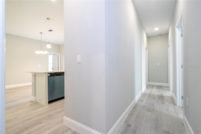 hall with an inviting chandelier and light hardwood / wood-style flooring