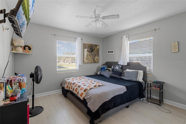 bedroom with a textured ceiling, light hardwood / wood-style floors, and ceiling fan