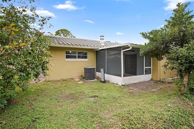 rear view of property with a sunroom, cooling unit, and a yard