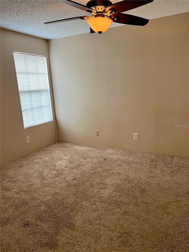 carpeted spare room featuring a textured ceiling and ceiling fan