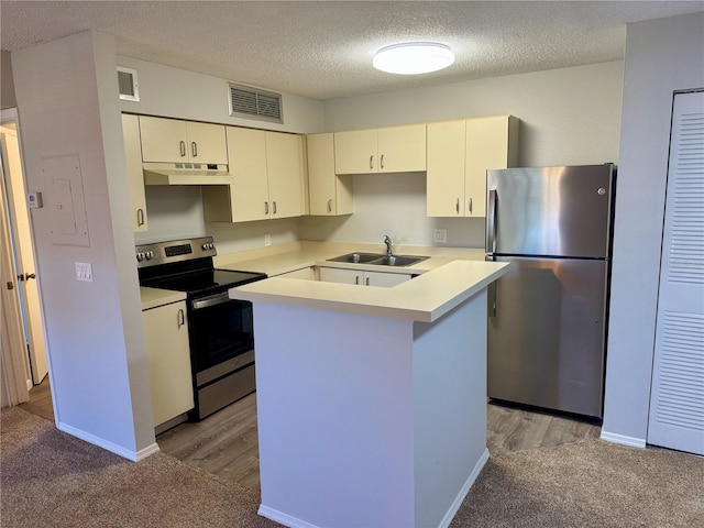 kitchen featuring light countertops, visible vents, appliances with stainless steel finishes, a sink, and under cabinet range hood