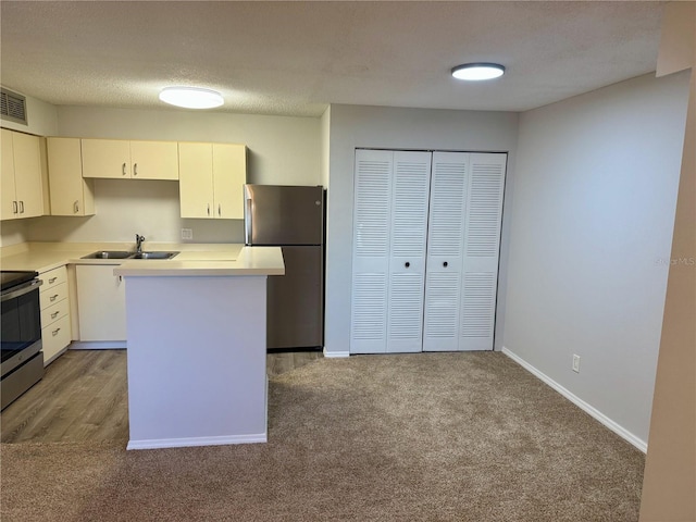 kitchen featuring appliances with stainless steel finishes, light colored carpet, light countertops, and a sink