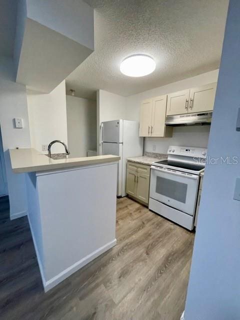 kitchen featuring kitchen peninsula, a textured ceiling, white appliances, sink, and light hardwood / wood-style flooring