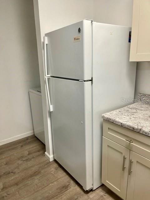 kitchen featuring white refrigerator, light hardwood / wood-style flooring, and light stone counters