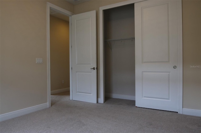 unfurnished bedroom featuring light carpet and a closet