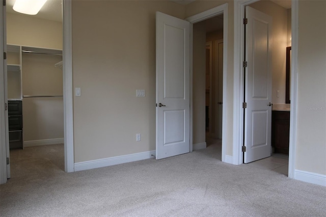 unfurnished bedroom with light carpet, a walk in closet, and a closet