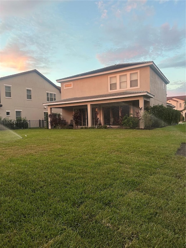 back house at dusk featuring a yard