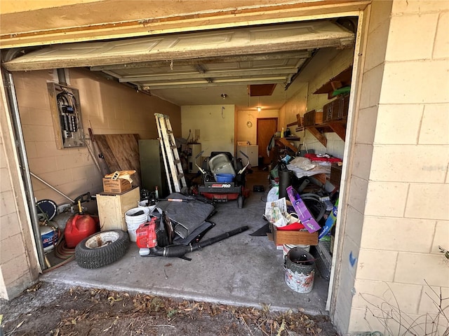 garage featuring concrete block wall, water heater, and electric panel