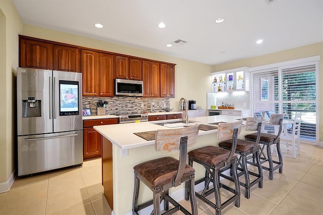 kitchen with sink, stainless steel appliances, a breakfast bar area, a kitchen island with sink, and light tile patterned flooring