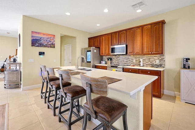 kitchen featuring a breakfast bar, stainless steel appliances, a kitchen island with sink, and sink