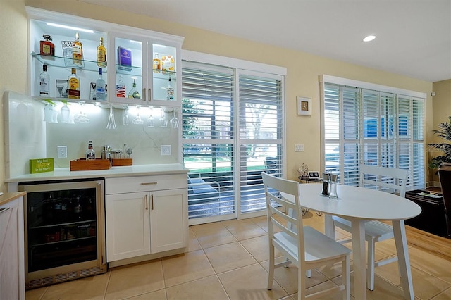 bar featuring white cabinets, light tile patterned floors, and beverage cooler