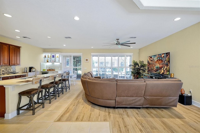 living room with ceiling fan, sink, and light hardwood / wood-style flooring