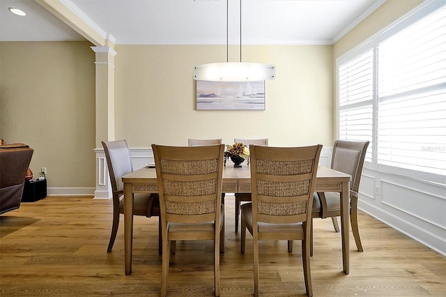 dining room with ornate columns, crown molding, and light hardwood / wood-style flooring