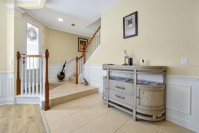 foyer with ornamental molding and light tile patterned floors