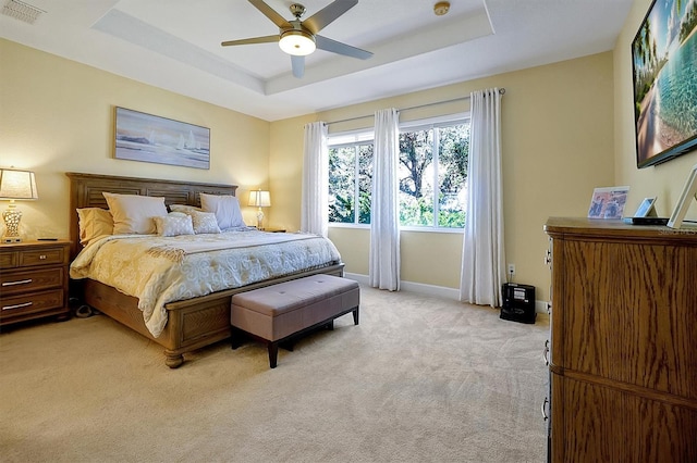 carpeted bedroom featuring ceiling fan and a raised ceiling