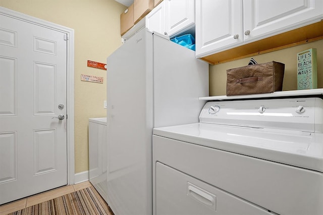 washroom with washer and clothes dryer, light tile patterned floors, and cabinets