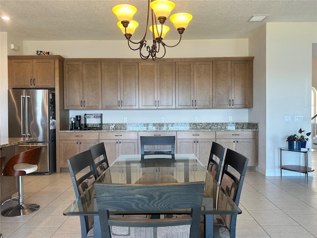 tiled dining area featuring a chandelier and a textured ceiling