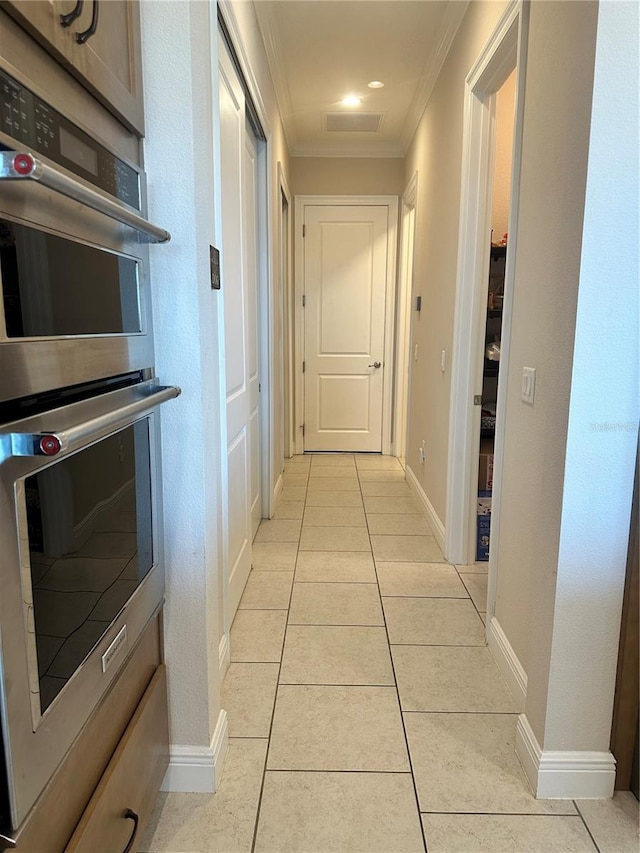 hall with light tile patterned floors and ornamental molding