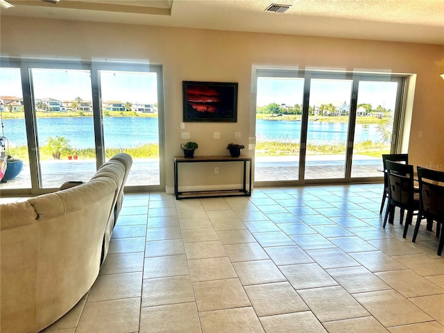 interior space with light tile patterned floors, a textured ceiling, and a water view