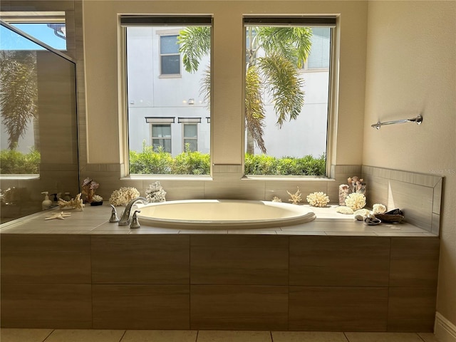 bathroom featuring tile patterned floors, a wealth of natural light, and tiled bath