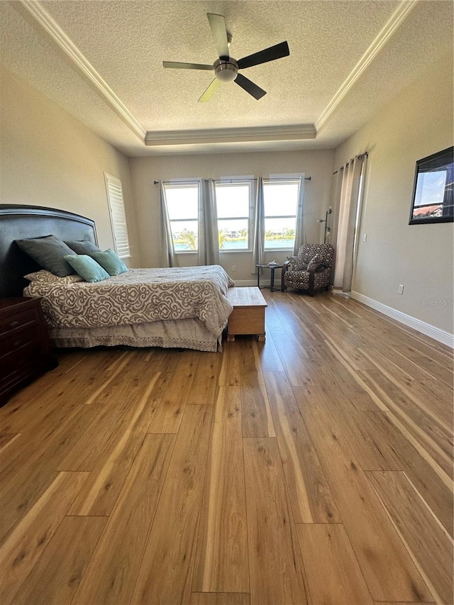 bedroom with hardwood / wood-style flooring, ceiling fan, a raised ceiling, and a textured ceiling