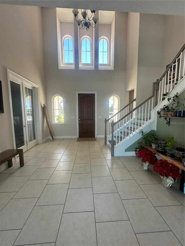 entryway with light tile patterned flooring, a chandelier, and a high ceiling