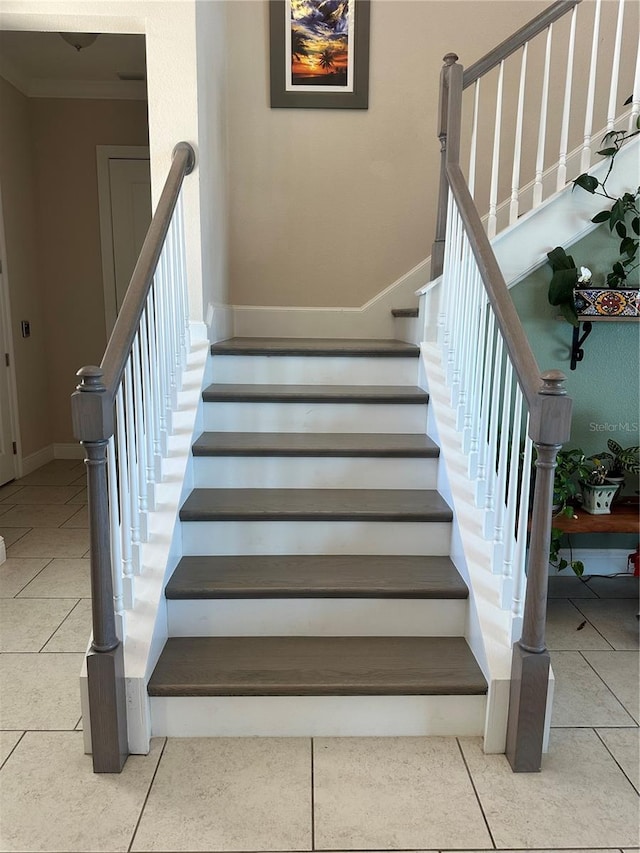 stairway with crown molding and tile patterned flooring