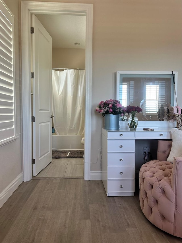 bathroom with hardwood / wood-style floors, shower / bath combination with curtain, and toilet