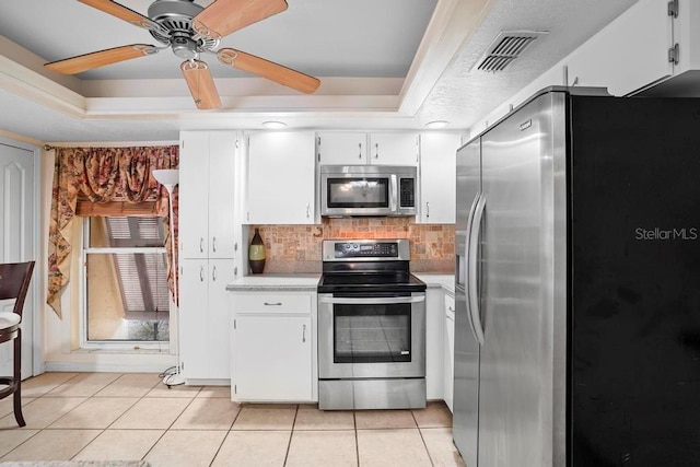 kitchen featuring appliances with stainless steel finishes, a raised ceiling, ceiling fan, light tile patterned floors, and white cabinetry