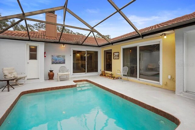 back of house with glass enclosure and a patio