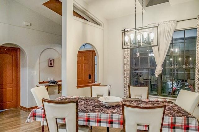 dining area featuring vaulted ceiling, wood-type flooring, and a notable chandelier