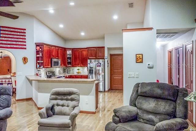 kitchen featuring light wood-type flooring, stainless steel appliances, kitchen peninsula, and tasteful backsplash