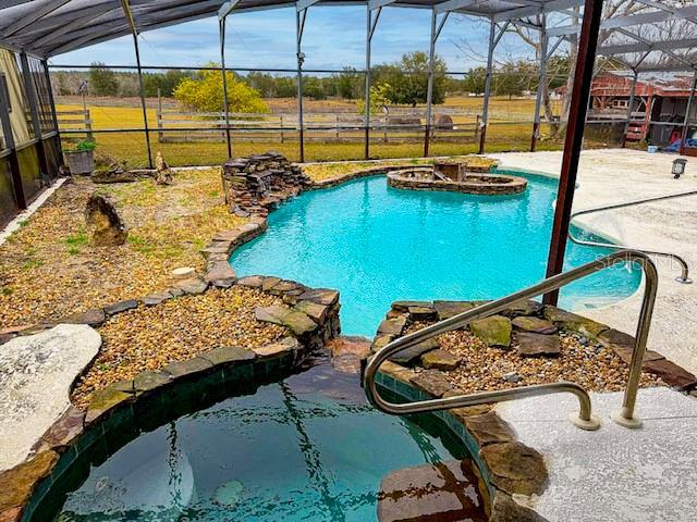 view of swimming pool featuring a hot tub, a patio, and glass enclosure