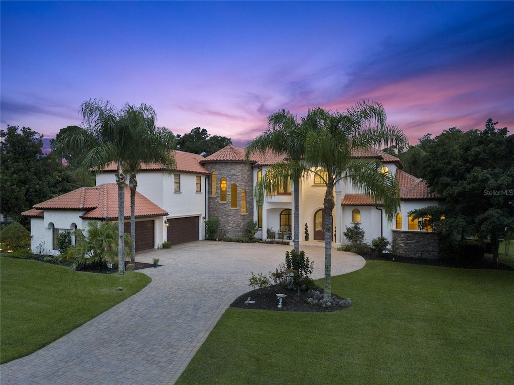 mediterranean / spanish home with a garage and a lawn