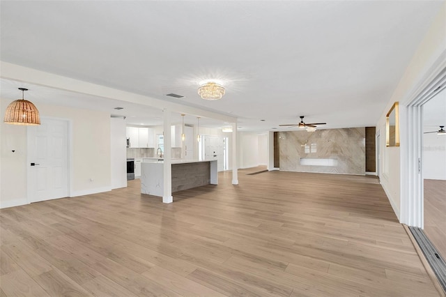 unfurnished living room featuring ceiling fan, light hardwood / wood-style flooring, and sink