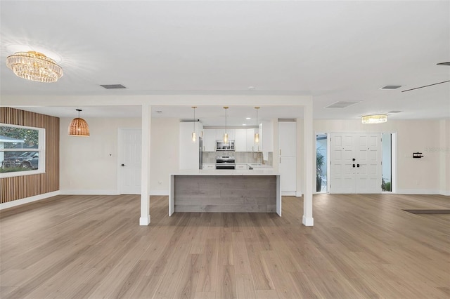 kitchen with decorative backsplash, white cabinets, pendant lighting, and appliances with stainless steel finishes